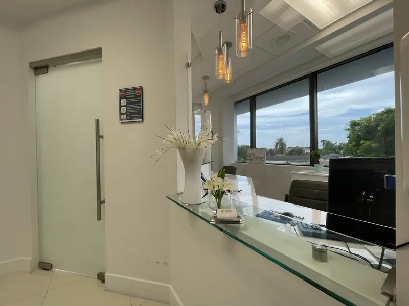 Reception area with frosted glass door and pendant lights, Miami clinic