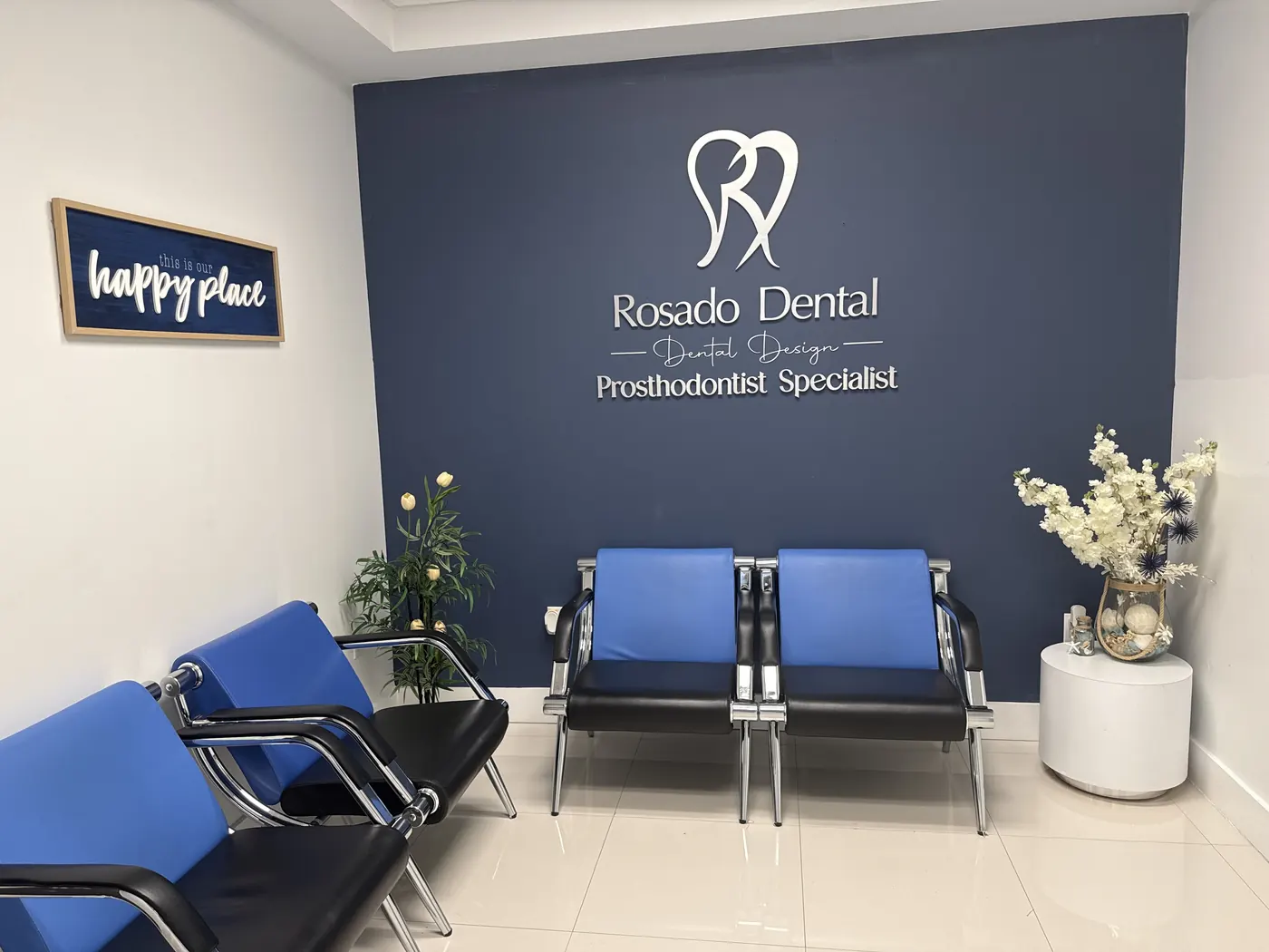 Waiting area at the Miami clinic: navy wall with the Rosado Dental logo, blue chairs and white orchids